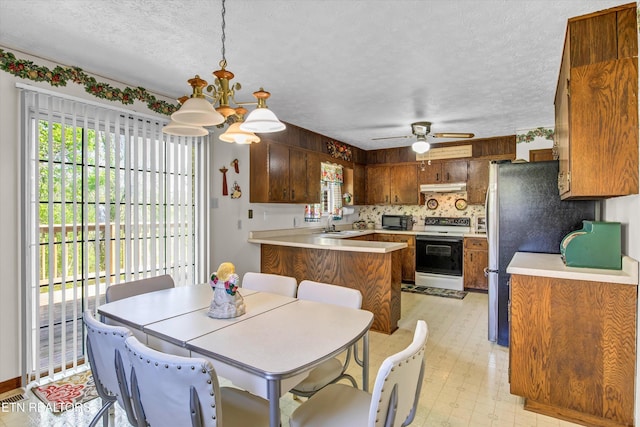 kitchen featuring light countertops, under cabinet range hood, a textured ceiling, and electric range oven