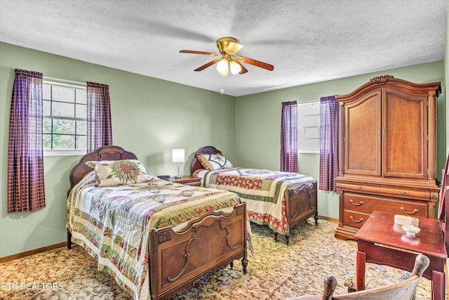 bedroom with baseboards, a textured ceiling, light colored carpet, and ceiling fan