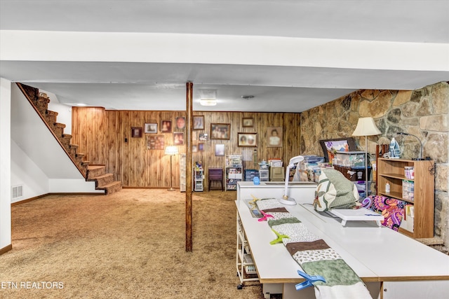 finished basement featuring stairs, wooden walls, baseboards, carpet flooring, and visible vents