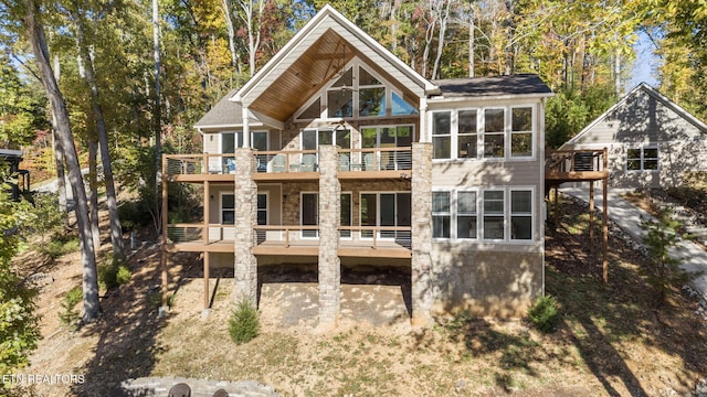back of property featuring stone siding, a wooden deck, and a balcony