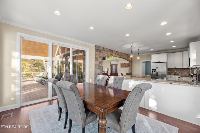 dining room with arched walkways, visible vents, a wealth of natural light, and ornamental molding