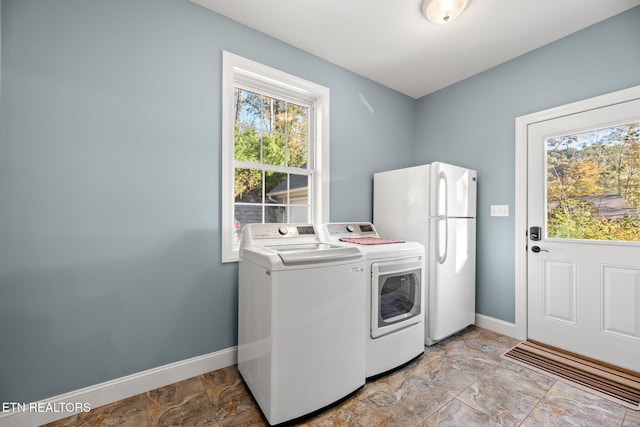 washroom with stone finish floor, baseboards, washer and dryer, and laundry area