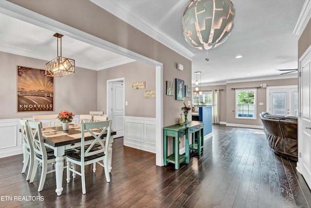 dining room featuring a chandelier, crown molding, a wainscoted wall, and dark wood-style floors