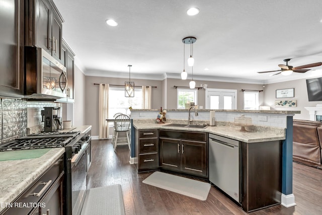 kitchen with dark brown cabinetry, stainless steel appliances, decorative backsplash, and a sink