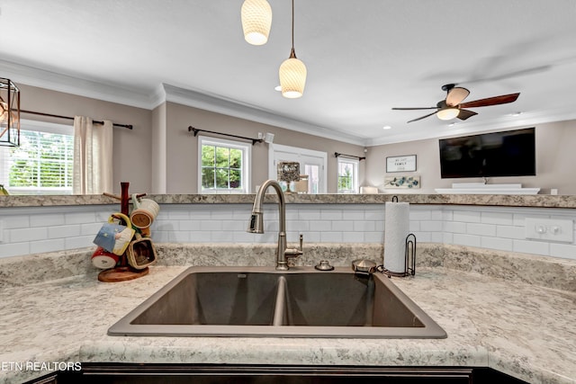 kitchen featuring decorative backsplash, a sink, ceiling fan, ornamental molding, and hanging light fixtures