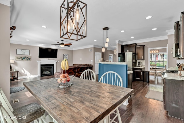 dining room with a glass covered fireplace, recessed lighting, dark wood-style flooring, and ceiling fan with notable chandelier
