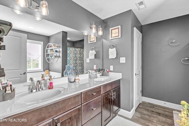 bathroom with wood finished floors, visible vents, baseboards, and a sink