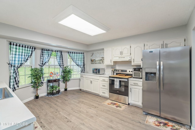 kitchen with light countertops, appliances with stainless steel finishes, under cabinet range hood, and white cabinets