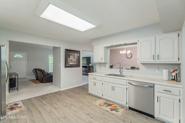 kitchen with white cabinets, a notable chandelier, a sink, light wood-style flooring, and stainless steel appliances