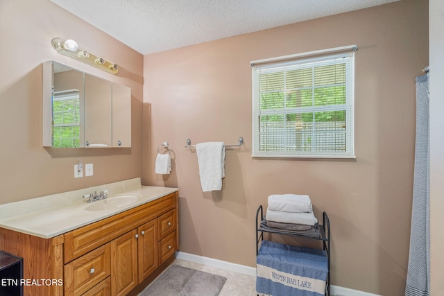 full bathroom with a textured ceiling, baseboards, and vanity