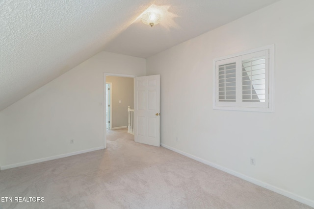 bonus room with light colored carpet, a textured ceiling, vaulted ceiling, and baseboards