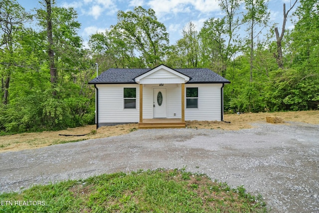 bungalow with driveway and roof with shingles