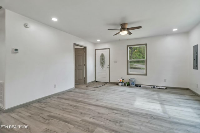unfurnished living room featuring a ceiling fan, wood finished floors, electric panel, baseboards, and recessed lighting