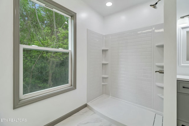 full bathroom with baseboards, vanity, marble finish floor, and a tile shower