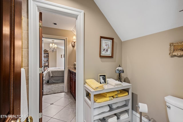 ensuite bathroom with tile patterned flooring, lofted ceiling, toilet, ensuite bath, and a notable chandelier
