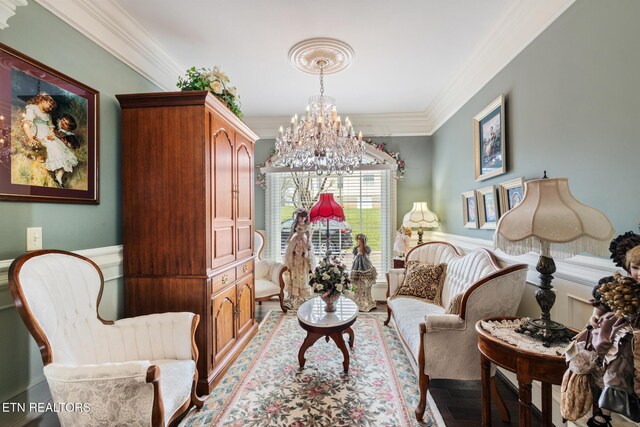 living area with ornamental molding, wainscoting, wood finished floors, and a notable chandelier