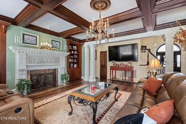 living area featuring ornate columns, ornamental molding, wood finished floors, and coffered ceiling