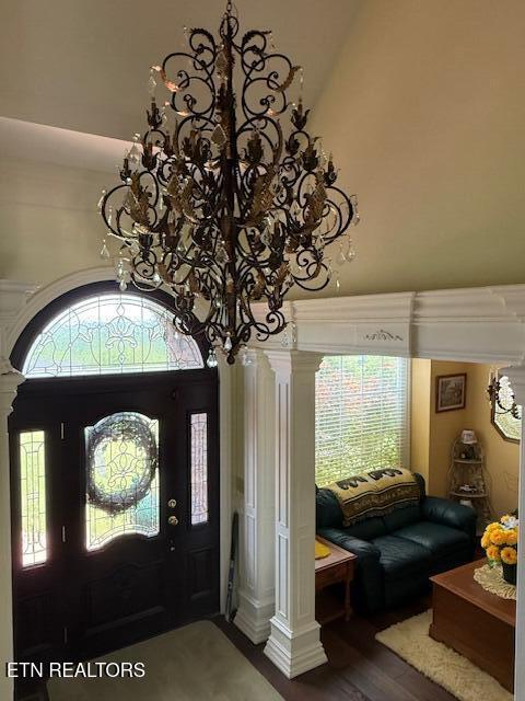 foyer entrance featuring decorative columns, a towering ceiling, and wood finished floors