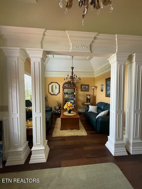 living room featuring crown molding, ornate columns, wood finished floors, and a chandelier