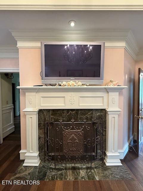 interior details with crown molding, a tiled fireplace, and wood finished floors