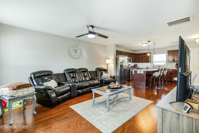 living room with dark wood-style floors, visible vents, and ceiling fan