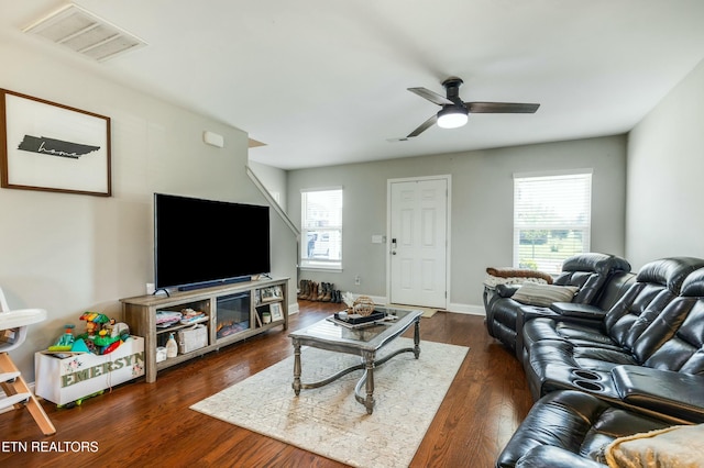 living area with dark wood-style floors, visible vents, ceiling fan, and baseboards