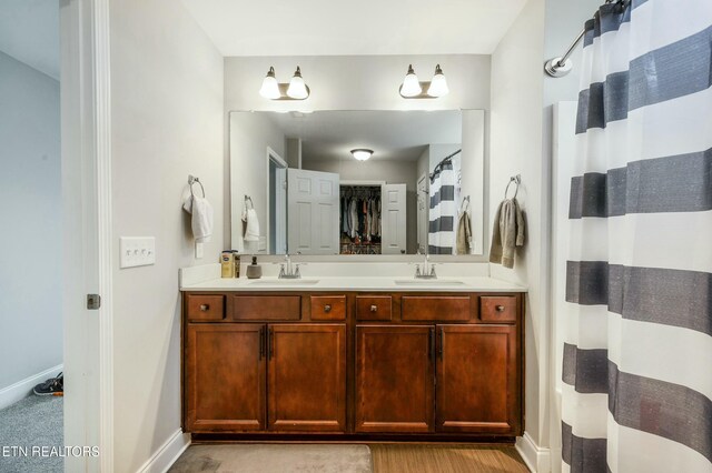 bathroom featuring double vanity, baseboards, and a sink