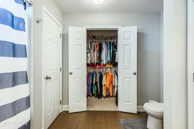 bathroom featuring toilet, wood finished floors, and baseboards