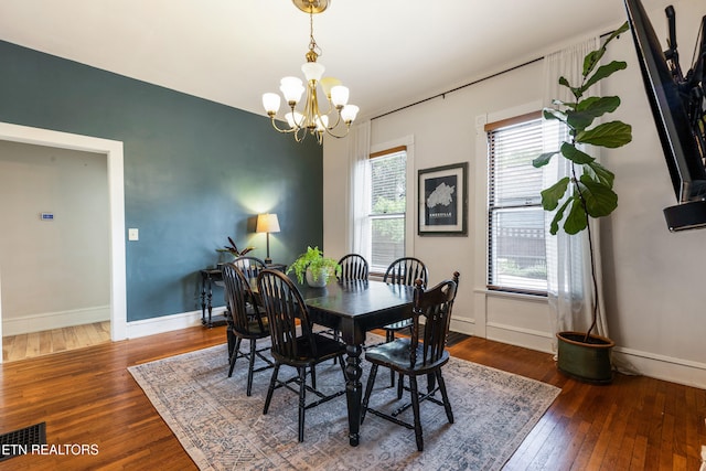 dining area with an inviting chandelier, visible vents, hardwood / wood-style flooring, and baseboards