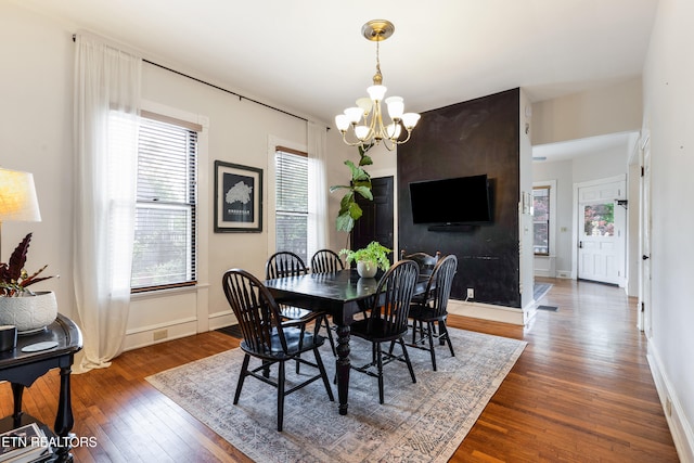dining area with a notable chandelier, baseboards, hardwood / wood-style flooring, and a healthy amount of sunlight