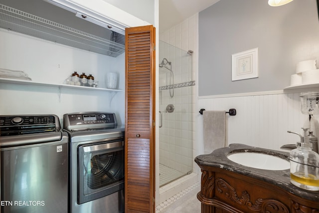 full bathroom featuring a stall shower, washer and dryer, wainscoting, and vanity