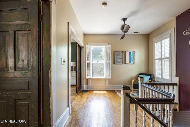 corridor with a wealth of natural light, wood finished floors, and baseboards