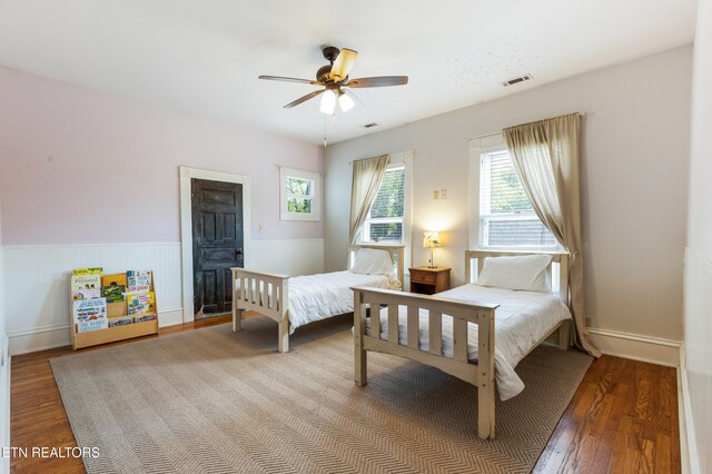 bedroom featuring a ceiling fan, visible vents, and wood finished floors