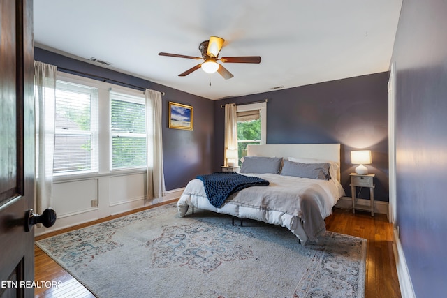 bedroom featuring baseboards, visible vents, wood finished floors, and ceiling fan
