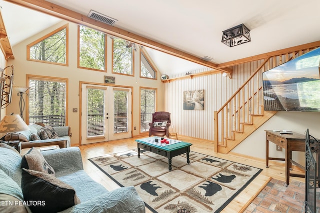 living room with wood finished floors, visible vents, stairs, french doors, and high vaulted ceiling