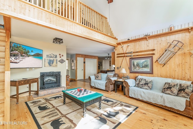 living room featuring wood walls, hardwood / wood-style flooring, a towering ceiling, and a fireplace
