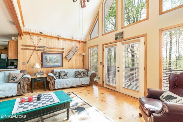 living room with wooden walls, wood finished floors, and french doors