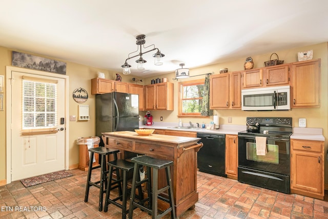 kitchen with light countertops, brick floor, a sink, and black appliances
