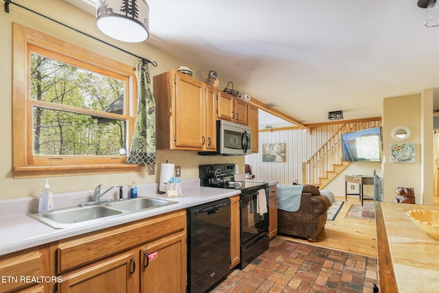 kitchen featuring brick floor, light countertops, a sink, and black appliances