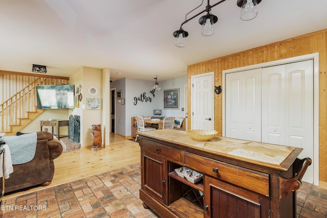 interior space with wooden walls, open floor plan, and brick floor