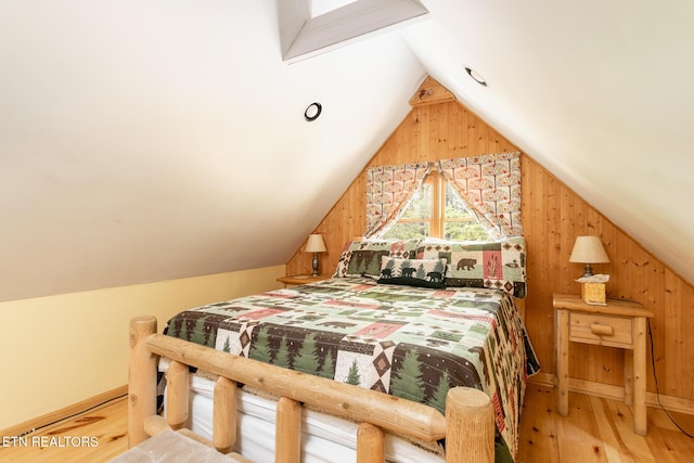bedroom featuring lofted ceiling, wooden walls, and wood finished floors