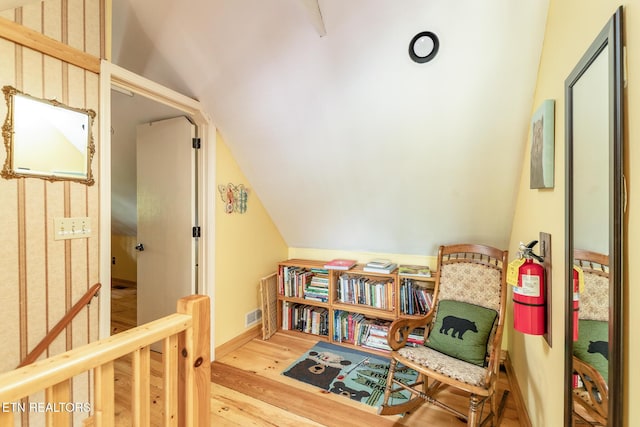 living area featuring lofted ceiling, baseboards, and wood finished floors