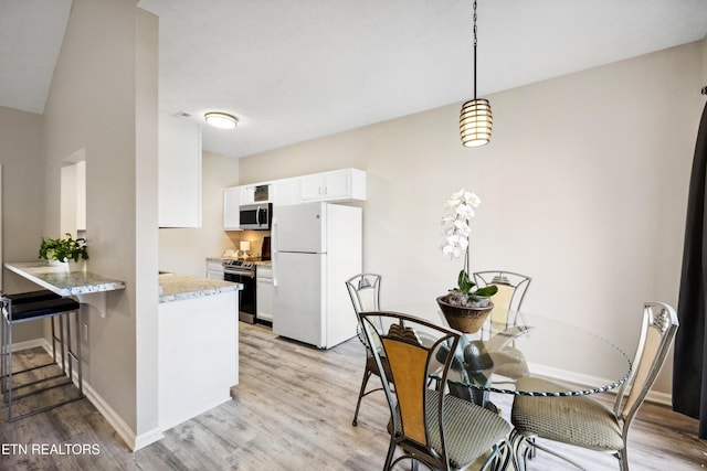 kitchen with white cabinets, light wood finished floors, stainless steel appliances, baseboards, and a peninsula