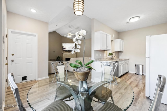 dining area with ceiling fan, baseboards, lofted ceiling, and light wood finished floors