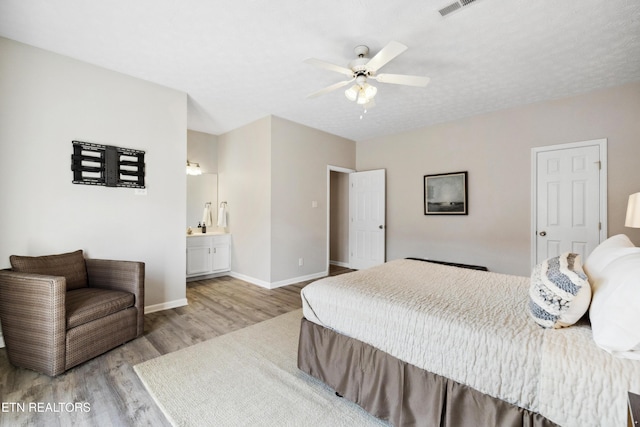 bedroom with light wood-type flooring, ensuite bathroom, baseboards, visible vents, and ceiling fan