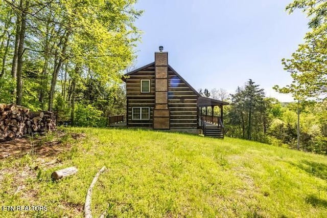rear view of property featuring a wooden deck, a yard, and a chimney