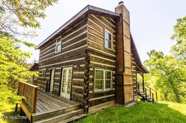 view of home's exterior with a chimney, a wooden deck, and french doors