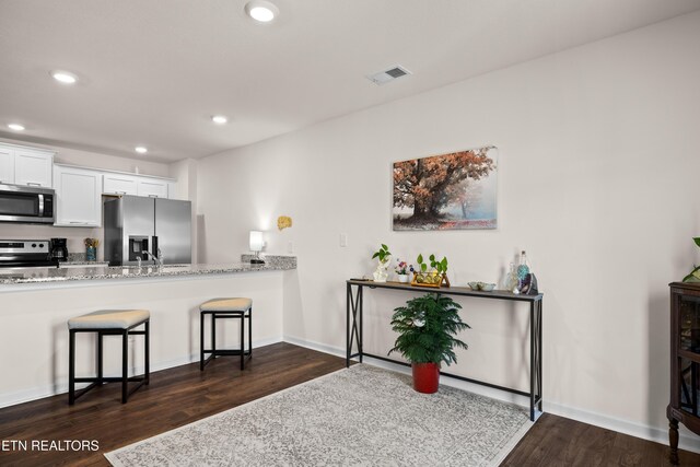 1423 Ridge Estates Dr, Athens, TN 37303 - kitchen featuring appliances with stainless steel finishes, dark wood-style floors, recessed lighting, a breakfast bar area, and light stone counters