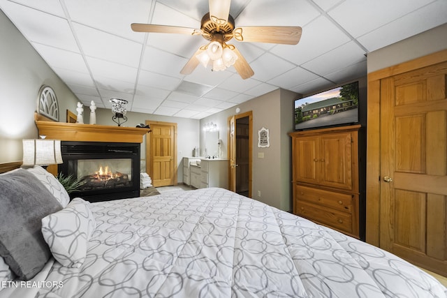 bedroom with a multi sided fireplace, ceiling fan, and a paneled ceiling