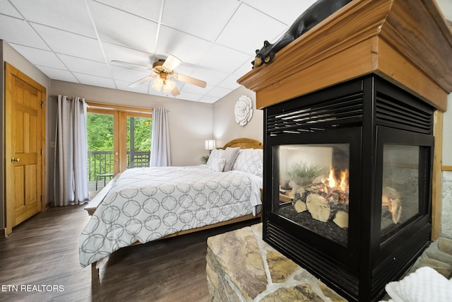 bedroom featuring access to outside, a ceiling fan, wood finished floors, and a paneled ceiling